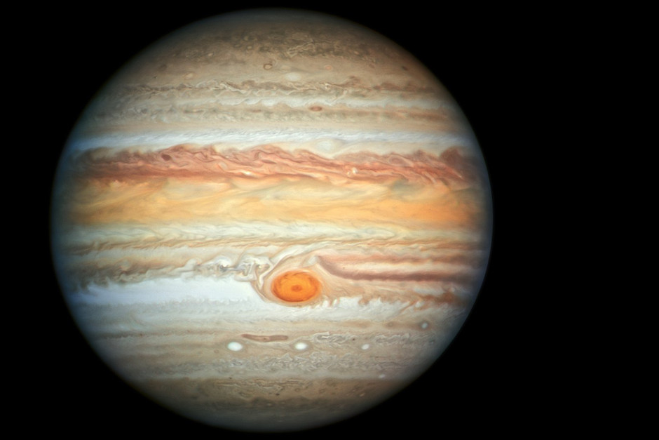 Jupiter med sina karaktäristiska horisontella linjer i rött och orange. I nedre delen av mitten en fläck liknade ett öga. Svart bakgrund.