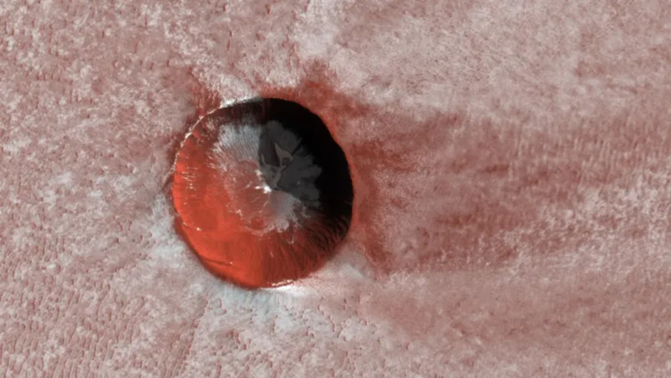 En isfylld krater på Mars. NASA:s Mars Reconnaissance Orbiter avbildade denna relativt unga, isfyllda krater nära Mars nordpol i december 2019. På håll ser den ut som en liten blodfläck på en tygbit.