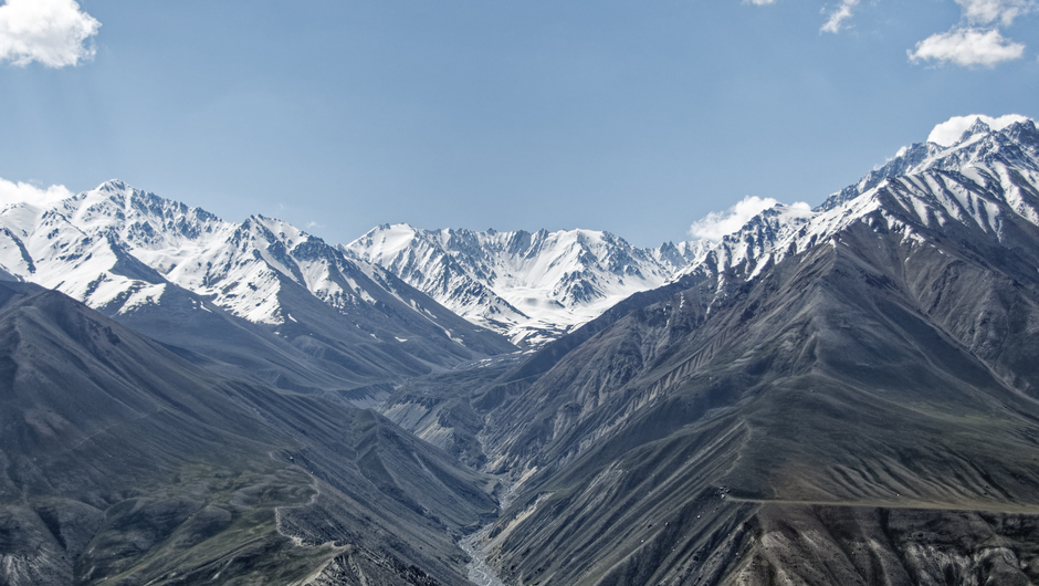 Bergskedjan Hindukush i Afghanistan sedd på avstånd med många spetsiga berg. Platsen är Tadzjikistan och den så kallade Wachan korridoren.