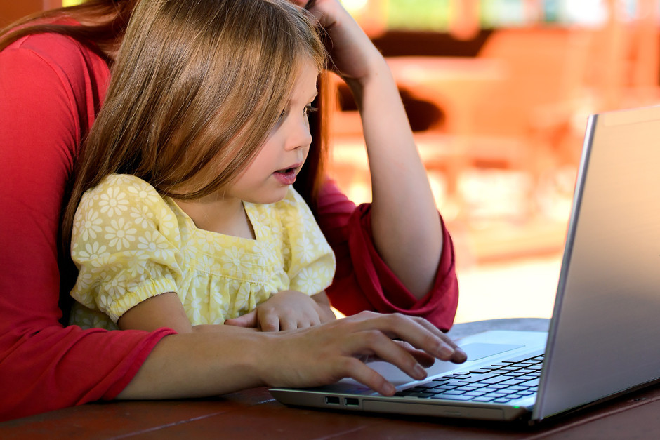 Foto av ett barn och vuxen som använder en laptop.