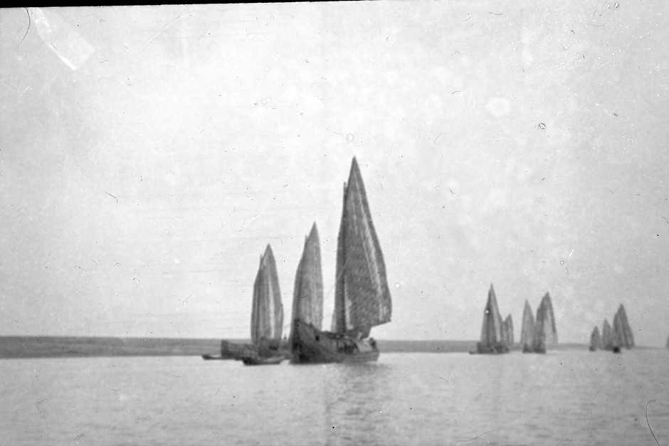 Gammalt svartvitt foto från 1800-talet på ett flertal enmastade skepp.